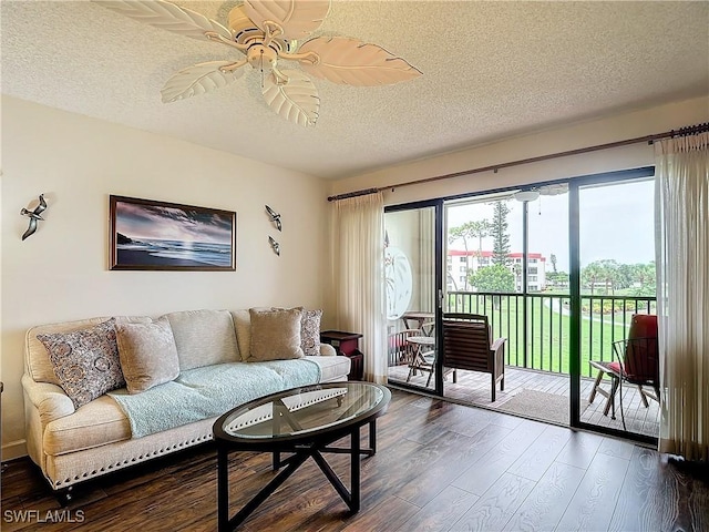 living room featuring ceiling fan, dark hardwood / wood-style flooring, and a textured ceiling