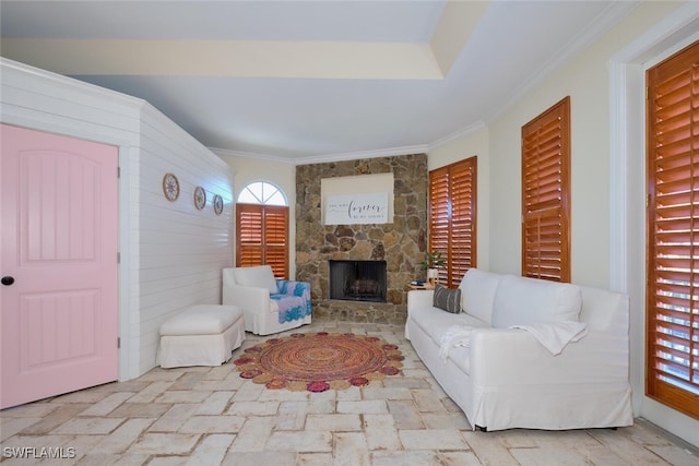 living room featuring crown molding and a stone fireplace