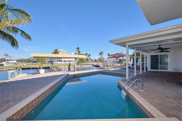 view of swimming pool with a water view, a boat dock, ceiling fan, and a patio area