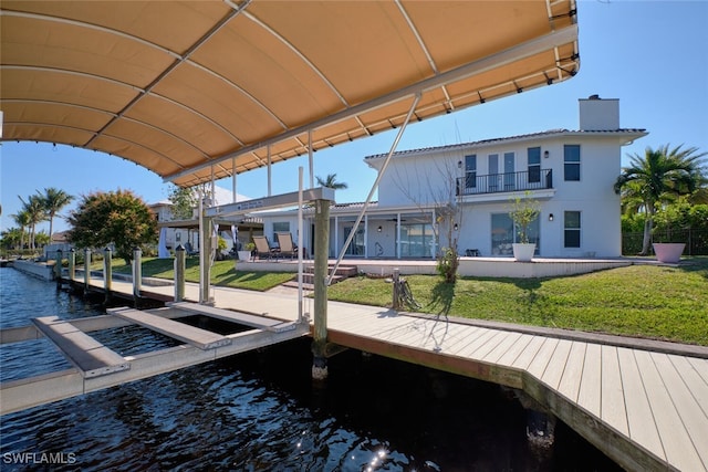 dock area with a yard, a balcony, and a water view