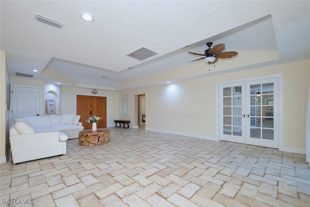 unfurnished living room with french doors, ceiling fan, and a tray ceiling