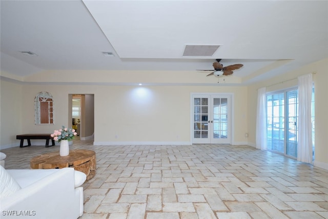 unfurnished living room featuring french doors, ceiling fan, and a raised ceiling