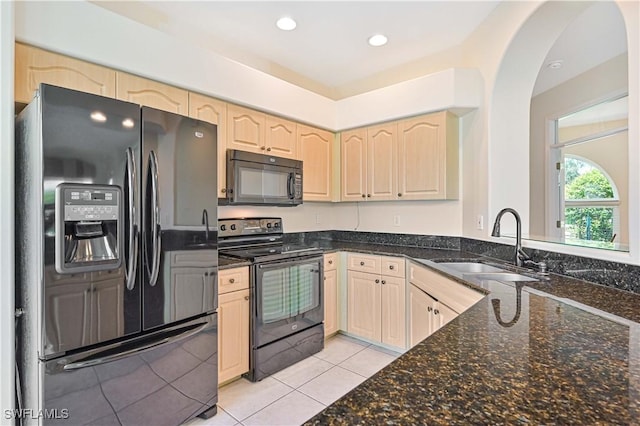 kitchen featuring light tile patterned flooring, sink, light brown cabinets, dark stone counters, and black appliances