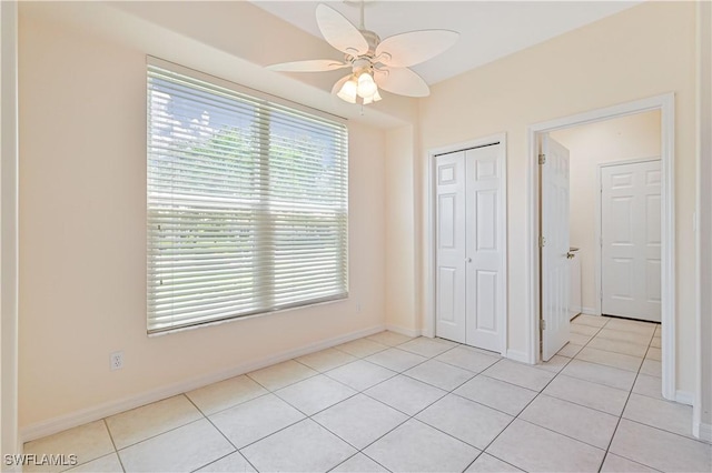 unfurnished bedroom with light tile patterned flooring, ceiling fan, and a closet