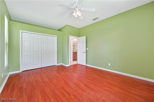 unfurnished bedroom featuring hardwood / wood-style floors, a closet, and ceiling fan