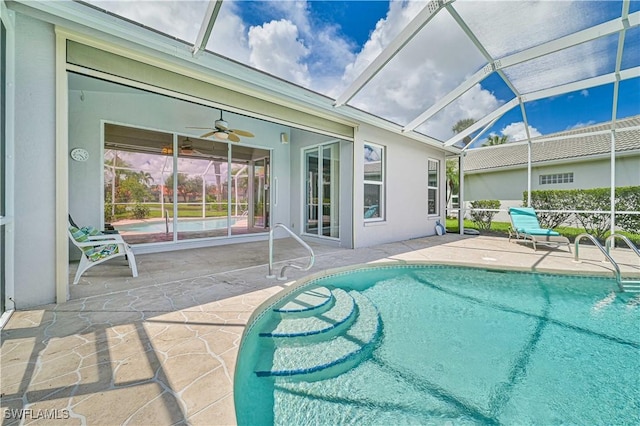 view of swimming pool with ceiling fan, a patio area, and glass enclosure