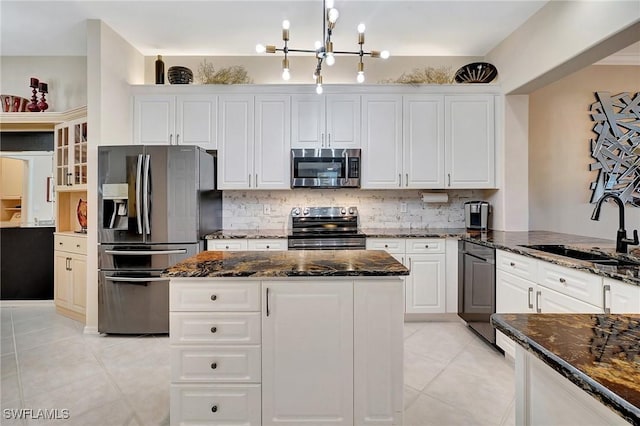 kitchen with sink, white cabinets, dark stone counters, light tile patterned floors, and stainless steel appliances