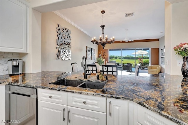 kitchen with sink, dark stone countertops, white cabinets, and decorative light fixtures