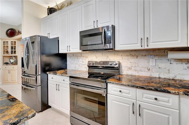 kitchen featuring stainless steel appliances, white cabinets, backsplash, and dark stone counters