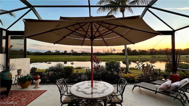 patio terrace at dusk with glass enclosure and a water view