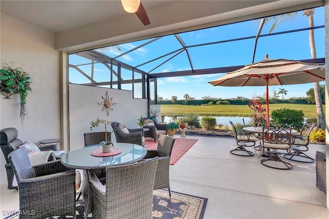 view of patio / terrace with a water view, ceiling fan, and a lanai