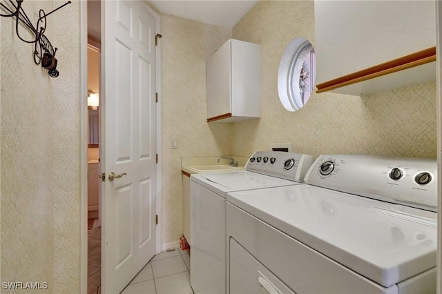 laundry area with cabinets, sink, light tile patterned floors, and washing machine and clothes dryer