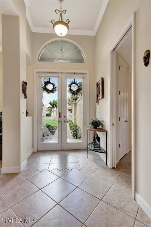 tiled foyer entrance featuring crown molding and french doors