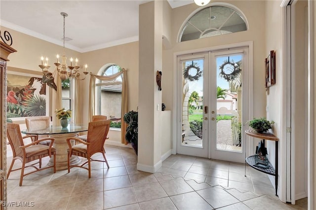 entrance foyer featuring french doors, crown molding, an inviting chandelier, and light tile patterned floors