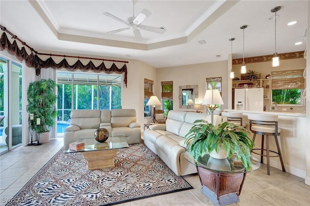 tiled living room featuring crown molding, sink, a tray ceiling, and ceiling fan