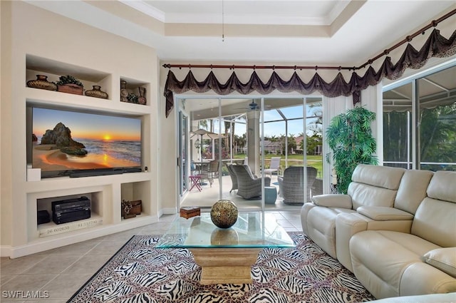 tiled living room with ornamental molding, built in features, a raised ceiling, and ceiling fan