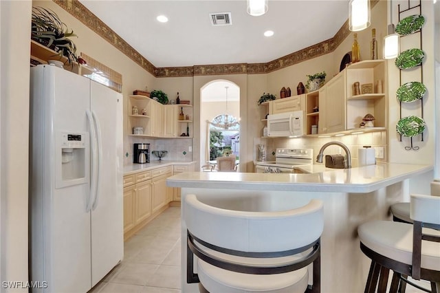 kitchen with a kitchen bar, tasteful backsplash, light tile patterned floors, pendant lighting, and white appliances