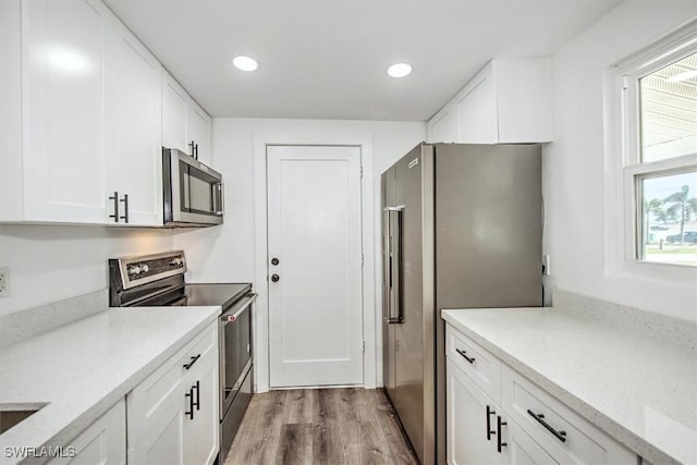 kitchen with light wood-type flooring, appliances with stainless steel finishes, white cabinets, and recessed lighting