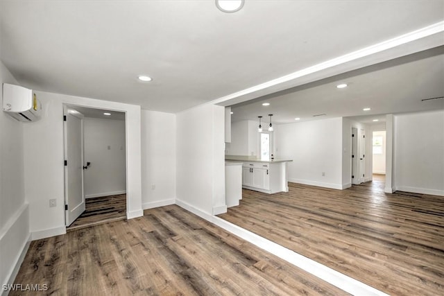 interior space featuring recessed lighting, baseboards, wood finished floors, and a wall mounted AC