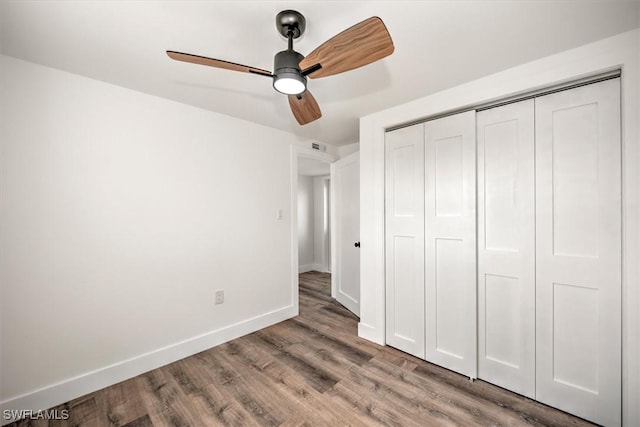 unfurnished bedroom with a closet, wood finished floors, a ceiling fan, and baseboards