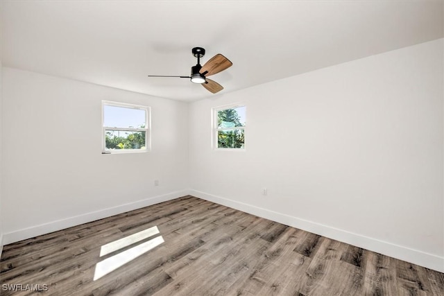 empty room featuring ceiling fan, baseboards, and wood finished floors