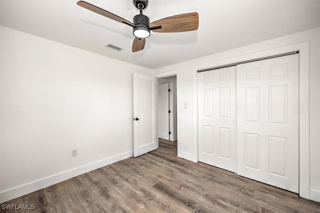 unfurnished bedroom with baseboards, visible vents, ceiling fan, wood finished floors, and a closet