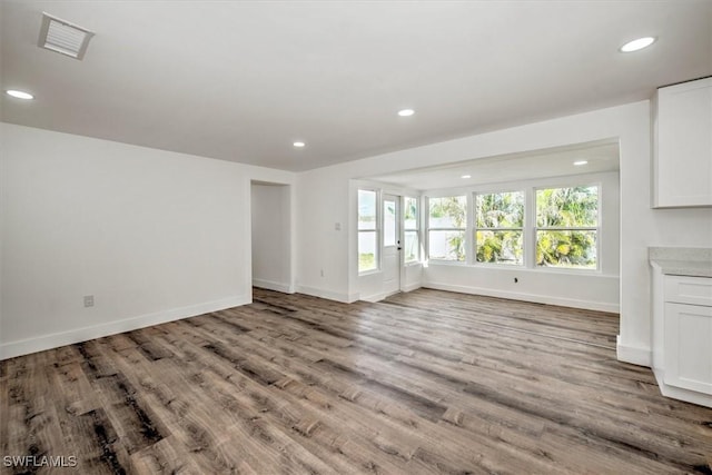 unfurnished living room featuring baseboards, visible vents, wood finished floors, and recessed lighting