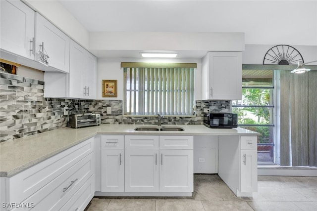 kitchen featuring sink, backsplash, light tile patterned floors, and white cabinets