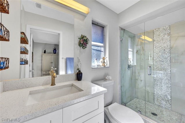 bathroom featuring a shower with door, vanity, and toilet