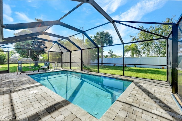 view of pool with a yard, a patio, and glass enclosure