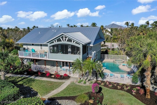 rear view of property with a patio, a pool with hot tub, a yard, and a balcony