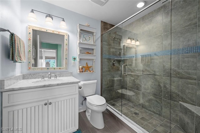 bathroom featuring vanity, a shower with door, and toilet