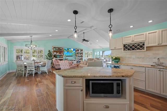 kitchen with a kitchen island, lofted ceiling with beams, hanging light fixtures, and light wood-type flooring