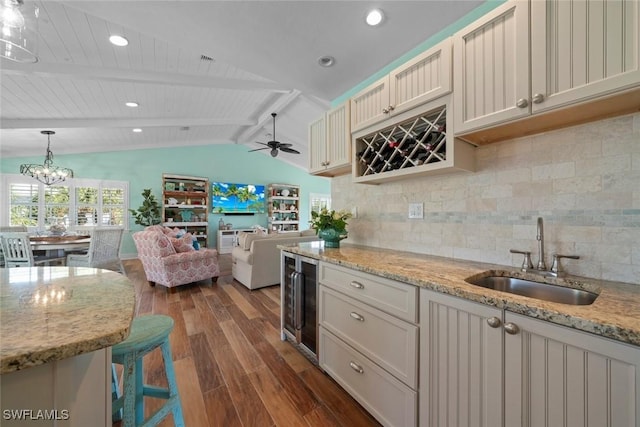 kitchen with light stone countertops, lofted ceiling with beams, decorative light fixtures, backsplash, and sink