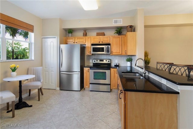 kitchen featuring sink, stainless steel appliances, tasteful backsplash, light tile patterned flooring, and kitchen peninsula