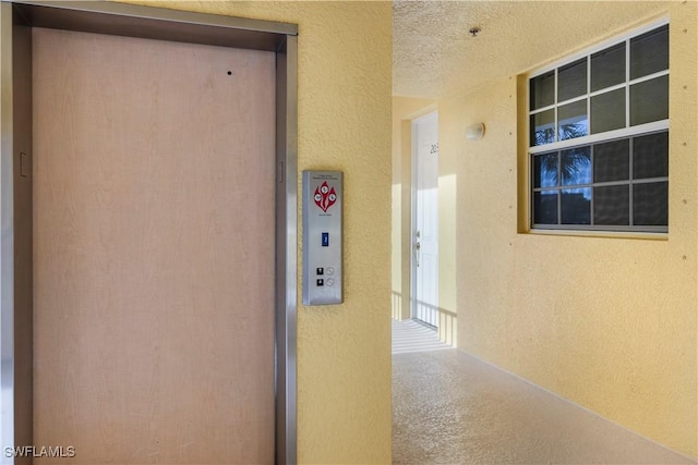 interior space with a textured ceiling and elevator