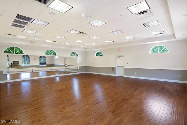 exercise room with dark hardwood / wood-style flooring and a drop ceiling