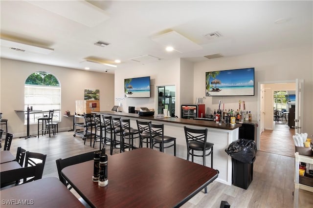 dining area with bar and light wood-type flooring