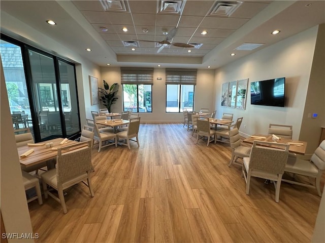 interior space featuring a tray ceiling, a drop ceiling, and light hardwood / wood-style flooring