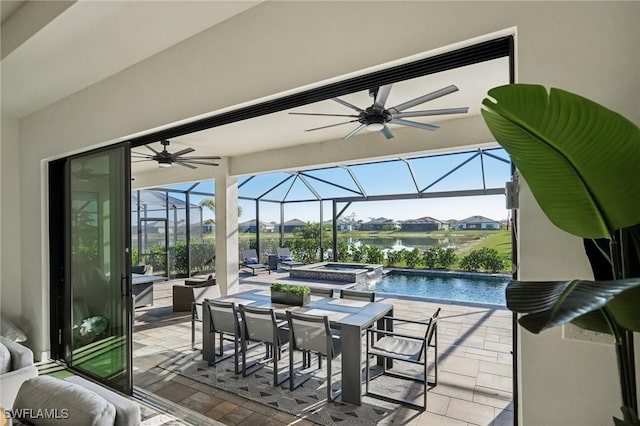 exterior space featuring a lanai, a patio area, an in ground hot tub, and a water view