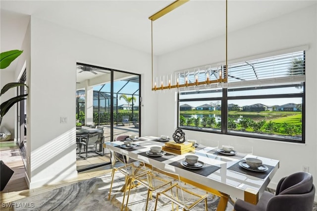 dining area with light hardwood / wood-style floors, ceiling fan, and a water view