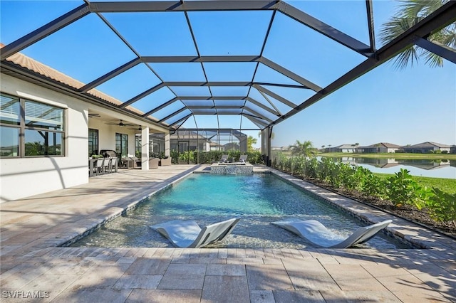 view of swimming pool featuring an in ground hot tub, ceiling fan, glass enclosure, a water view, and a patio area