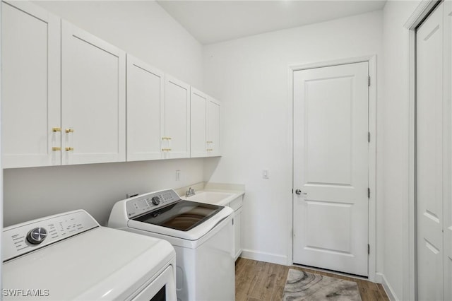 laundry area with cabinets, sink, washer and clothes dryer, and light hardwood / wood-style flooring