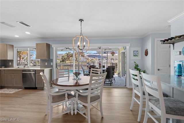 dining area featuring crown molding, sink, light hardwood / wood-style floors, and a notable chandelier