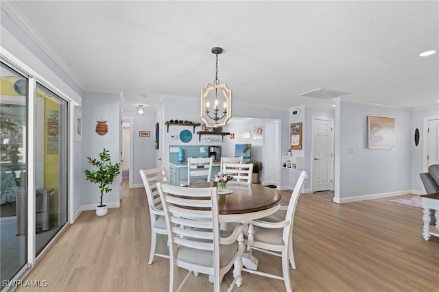 dining area featuring crown molding, a notable chandelier, and light wood-type flooring