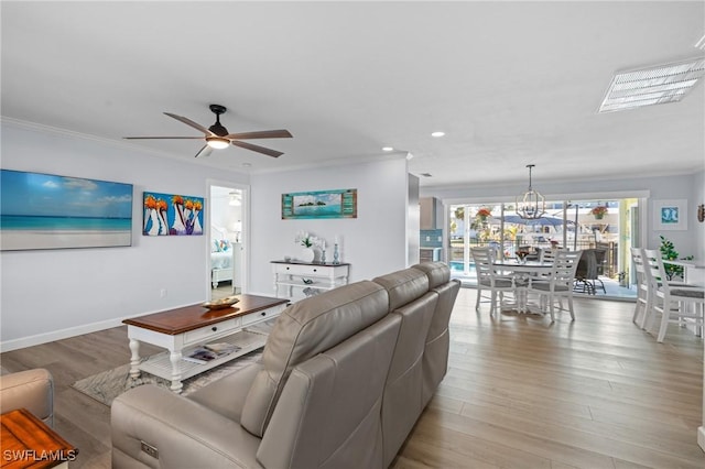 living room featuring ornamental molding, ceiling fan with notable chandelier, and light wood-type flooring