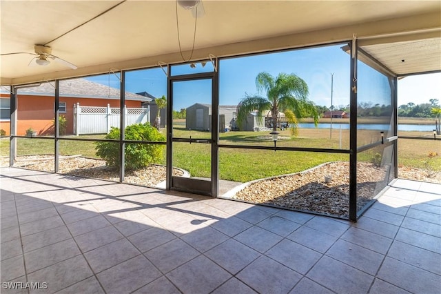 unfurnished sunroom with a water view and ceiling fan