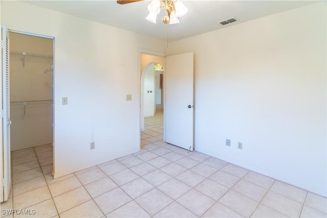 unfurnished bedroom with a walk in closet, ceiling fan, and a closet