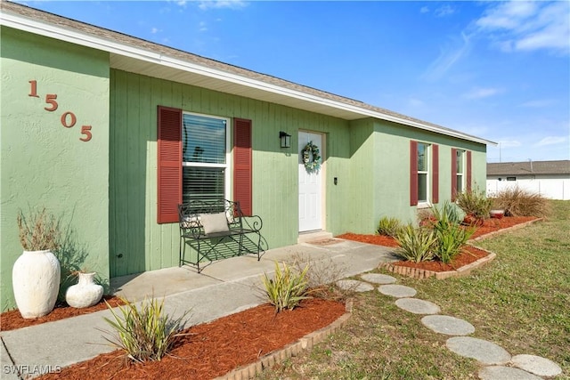 view of exterior entry featuring a yard and a porch