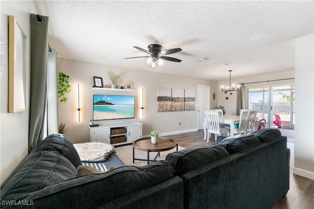 living room with hardwood / wood-style flooring, ceiling fan with notable chandelier, and a textured ceiling